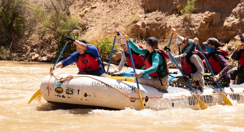 a group of veterans paddle a raft on an outward bound course